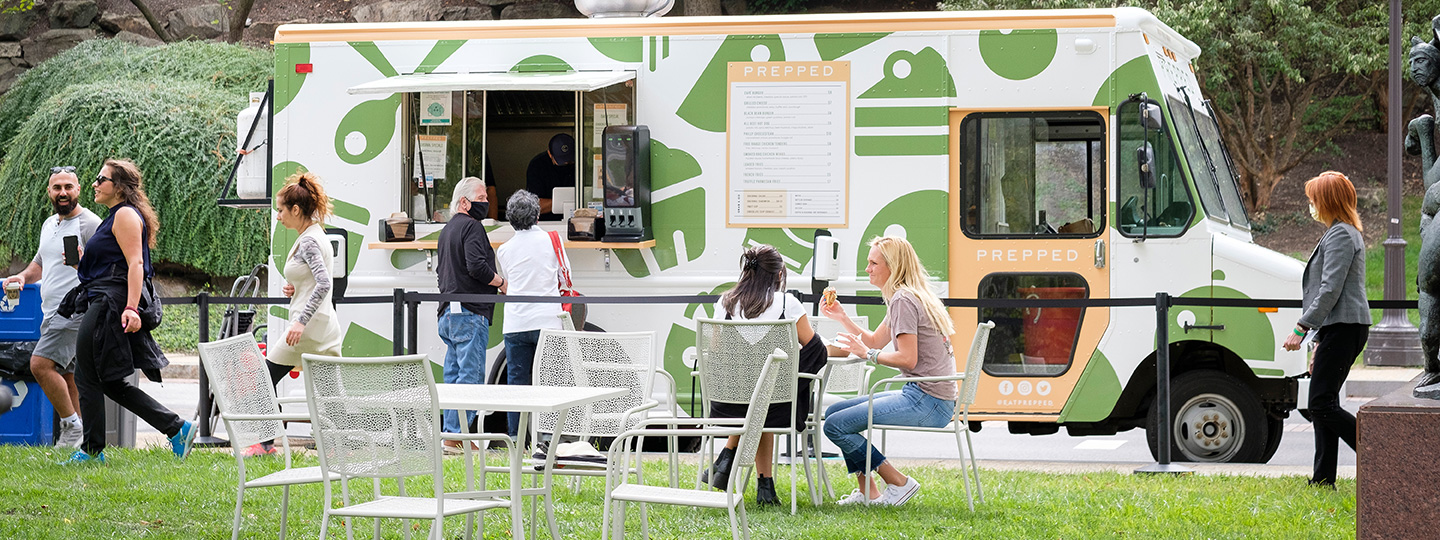 People ordering from a food truck and eating at tables